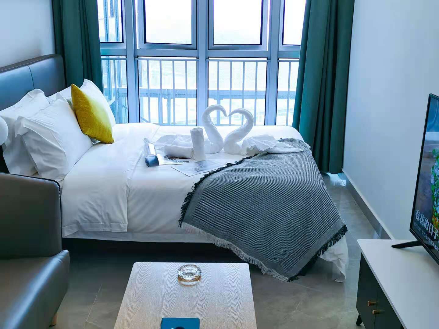 A hotel room with a bed, a sofa, a coffee table, and a TV.