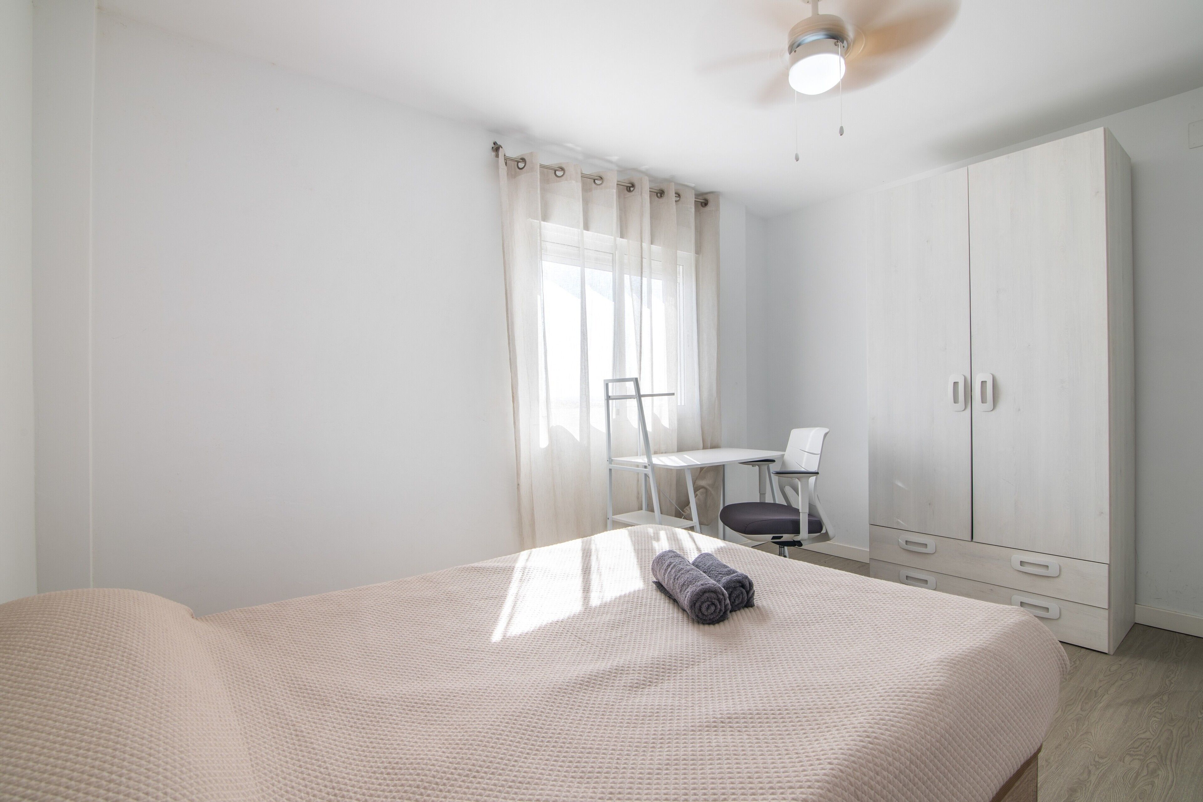 Un dormitorio con cama, escritorio, silla y armario.