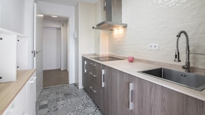 Et moderne køkken med en stålvask, træskabe og et mønstret backsplash.