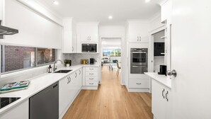 Eine moderne Küche mit weißen Schränken, einem Geschirrspüler, einer Mikrowelle und einem Backofen.