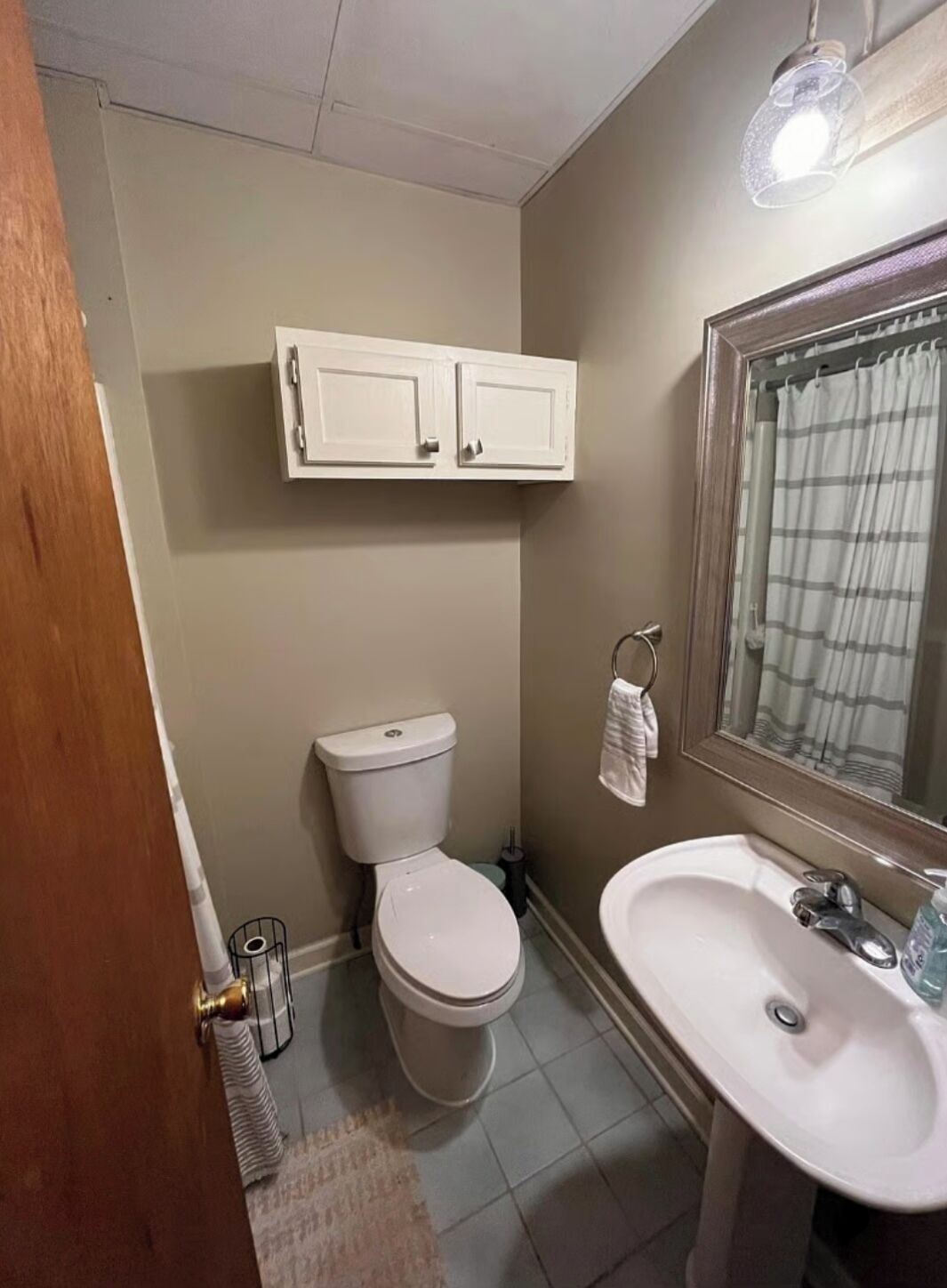 A bathroom with a toilet, sink, and a mirror above the sink.
