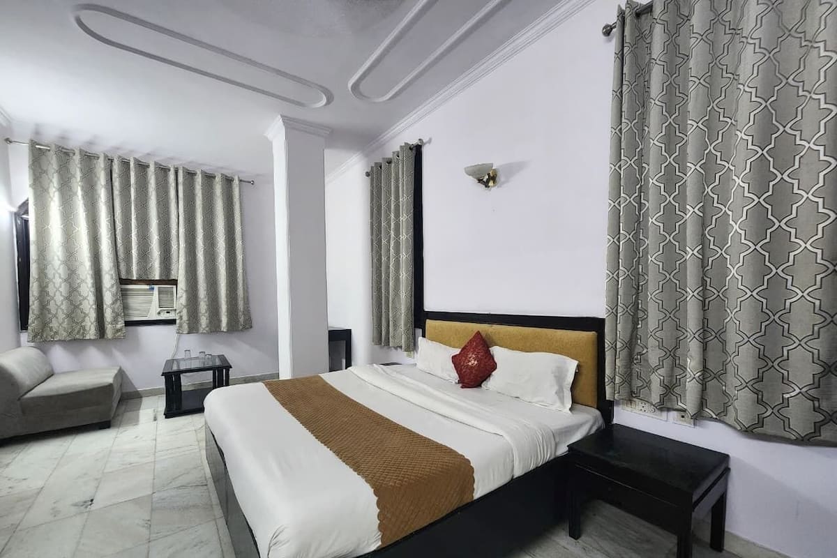 Une chambre d’hôtel équipée d’un lit, d’un canapé, d’une table de chevet et d’un radiateur fixé au mur.