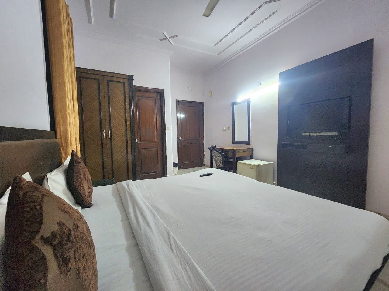A hotel room with a bed, a desk, a chair, a wardrobe, and a television.
