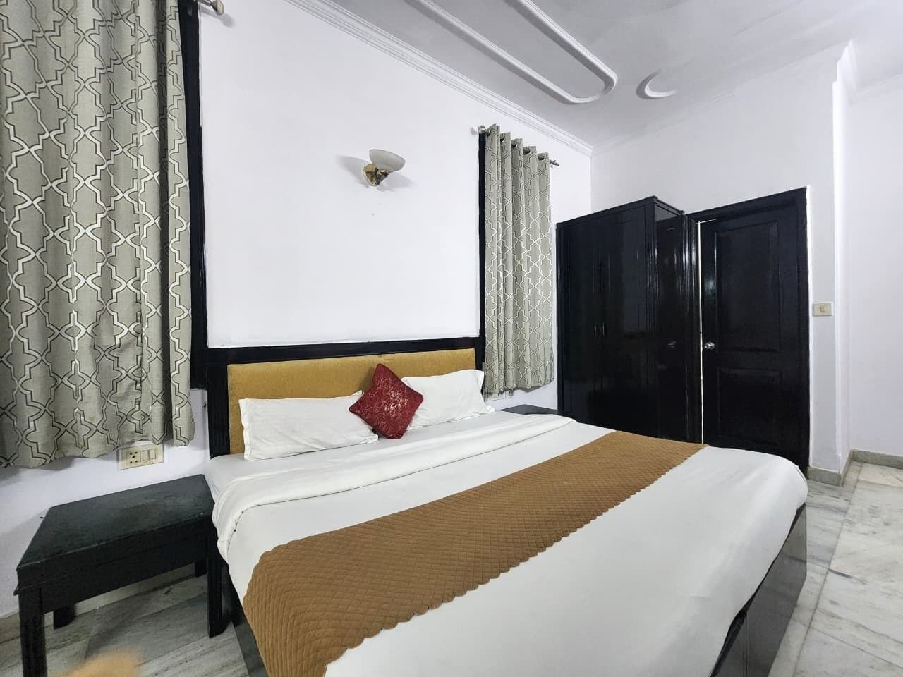 A neatly made bed with a headboard, a bedside table, and a wall-mounted light fixture.