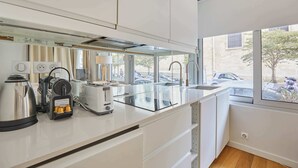 Een moderne keuken met een glazen aanrecht, ingebouwde apparatuur en uitzicht op geparkeerde auto's.