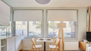 Een moderne keuken met een eethoek, grote ramen en een televisie op een houten kast.