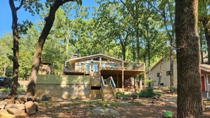A cabin with a deck, surrounded by trees and rocks.