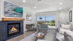 A living room with a fireplace, a large TV, a desk, and a comfortable seating area.