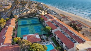 A coastal residential area with a tennis court, swimming pool, and beach access.