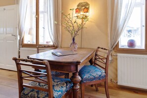 A dining table with chairs, a vase with branches, and a lamp on the wall. - Holiday Apartment 'Am Roten Schloss' with Shared Terrace, Shared Garden and Wi-Fi (Baruth/Mark)
