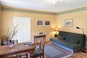 A room with a dining table, chairs, a sofa, a lamp, and framed pictures on the wall. - Holiday Apartment 'Am Roten Schloss' with Shared Terrace, Shared Garden and Wi-Fi (Baruth/Mark)