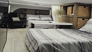 A modern bedroom with two beds, a small table, and storage baskets.
