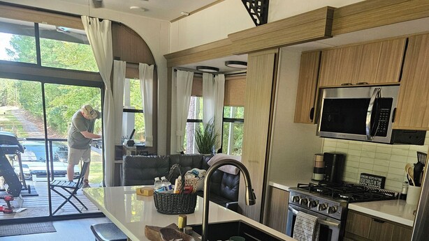 A modern kitchen with a central island, stainless steel appliances, and a dining area with a view of the outdoors.