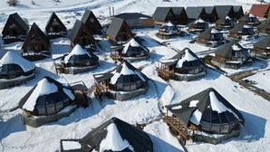 Un grupo de yurtas cubiertas de nieve con techos cónicos, dispuestas en una ladera nevada.