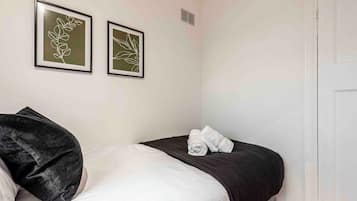 Habitació d'hotel amb llit, almoina negra, dues obres d'art emmarcades i una porta blanca.