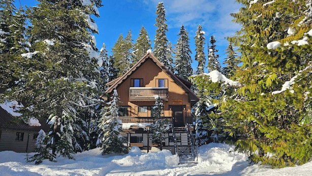 A wooden chalet with a balcony, surrounded by snow-covered trees. - Snowflake Chalet -Govy Chalet Steps to Glade Trail (Government Camp)