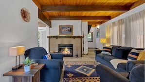 A cozy living room with a fireplace, wooden ceiling beams, and a patterned rug. - Snowflake Chalet -Govy Chalet Steps to Glade Trail (Government Camp)