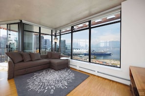 Una sala de estar moderna con un sofá seccional, una mesita redonda y un ventanal con vistas a la ciudad.