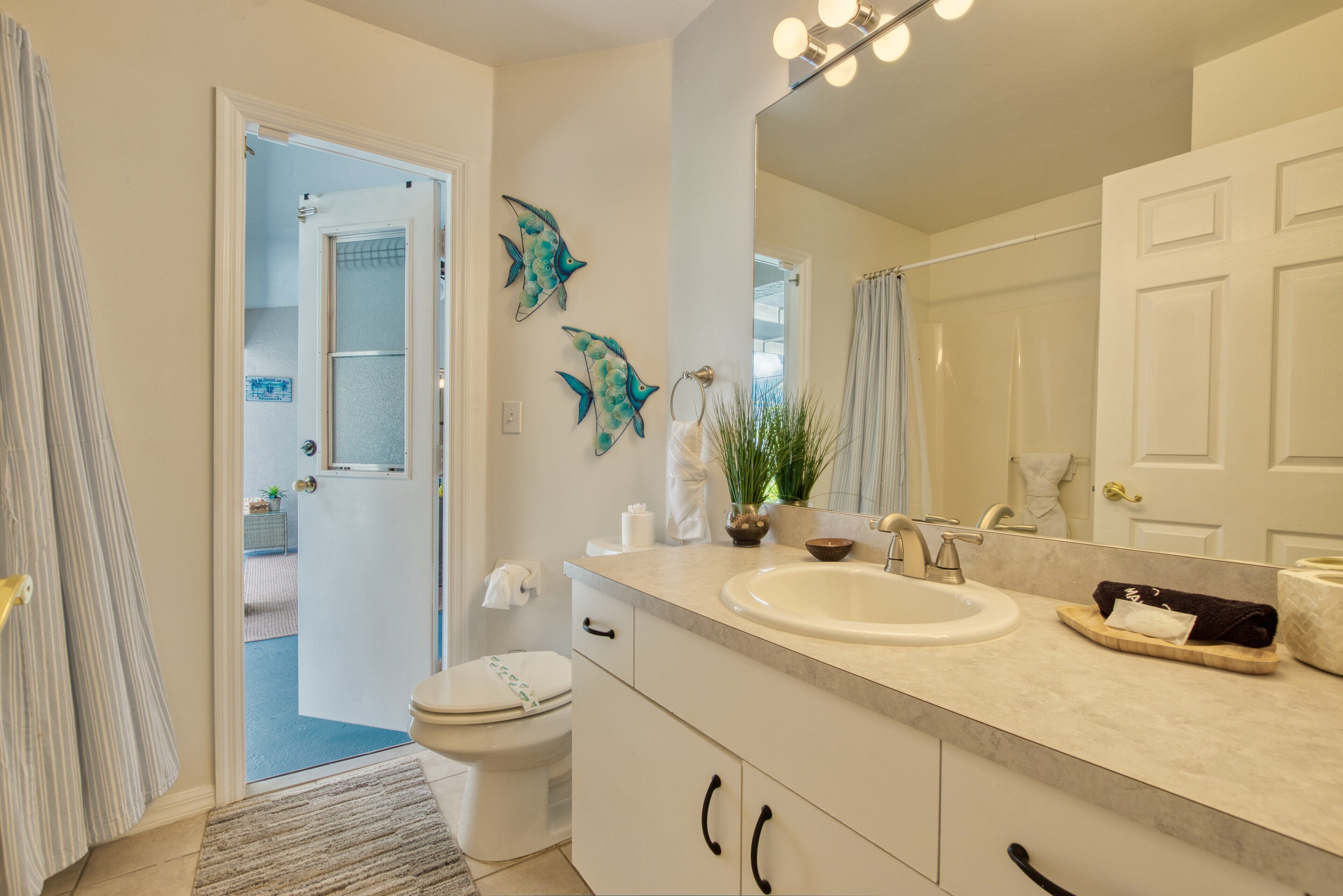 A bathroom with a white sink, a mirror, and decorative fish wall art.