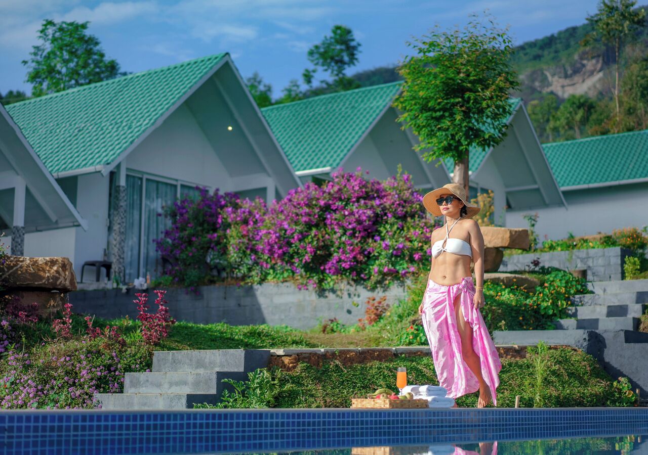 A person standing by a pool with a house in the background.