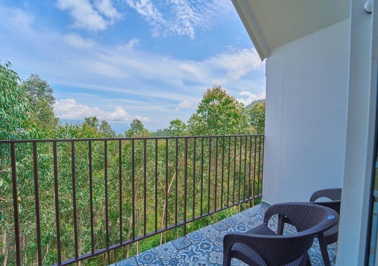 A balcony with a patterned floor, metal railing, and wicker chairs.