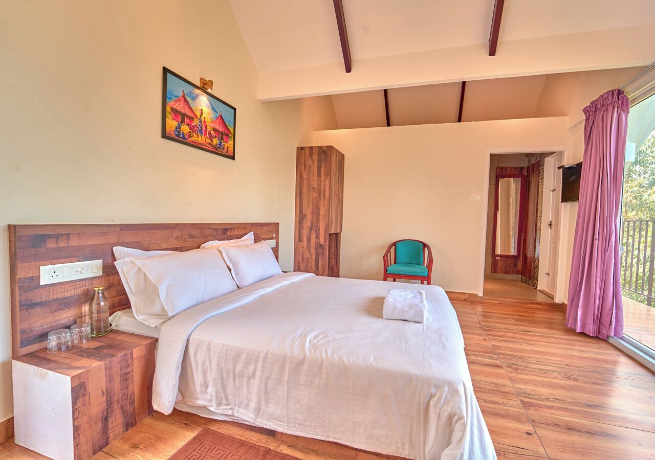 Une chambre à coucher avec une tête de lit en bois, un grand lit, une table de chevet, une chaise et une vue sur l’extérieur.