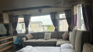 Une chambre à coucher avec un lit, un canapé, une télévision et une fenêtre avec des rideaux.