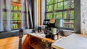 A kitchen area with a coffee maker, a guitar, and a window with curtains. - Intimate Cabin Escape: Hot Tub, Sauna, Firepit, Grill & Projector (Mentone)