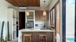 A modern kitchen with a central island, wooden cabinets, and two bar stools. - 2-bedroom Villa Athaya in peaceful Bali (Bali)