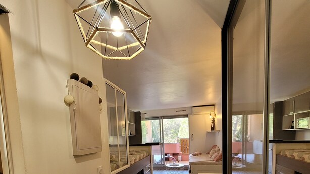 A spacious room with a wooden floor, a hanging light fixture, a sliding door, and a view of the outdoors.