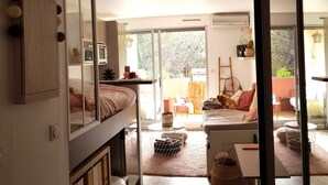 A modern, well-lit room with a bunk bed, a sofa, and a dining area.