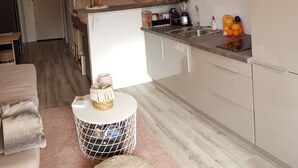 A compact kitchen with a microwave, sink, and a television mounted above the counter.