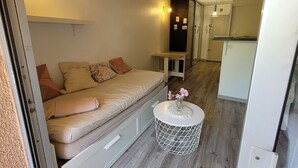A compact bedroom with a bed, bedside table, and a small round table with a vase.