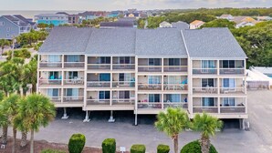 A multi-story hotel with balconies, a parking area, and a view of the sea. - Surfwalk 343 – Shared Pool, 2 Balconies & Easy Beach Access (Surfside Beach)
