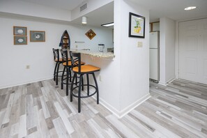 Een keuken met een bar, houten vloeren en een koelkast.