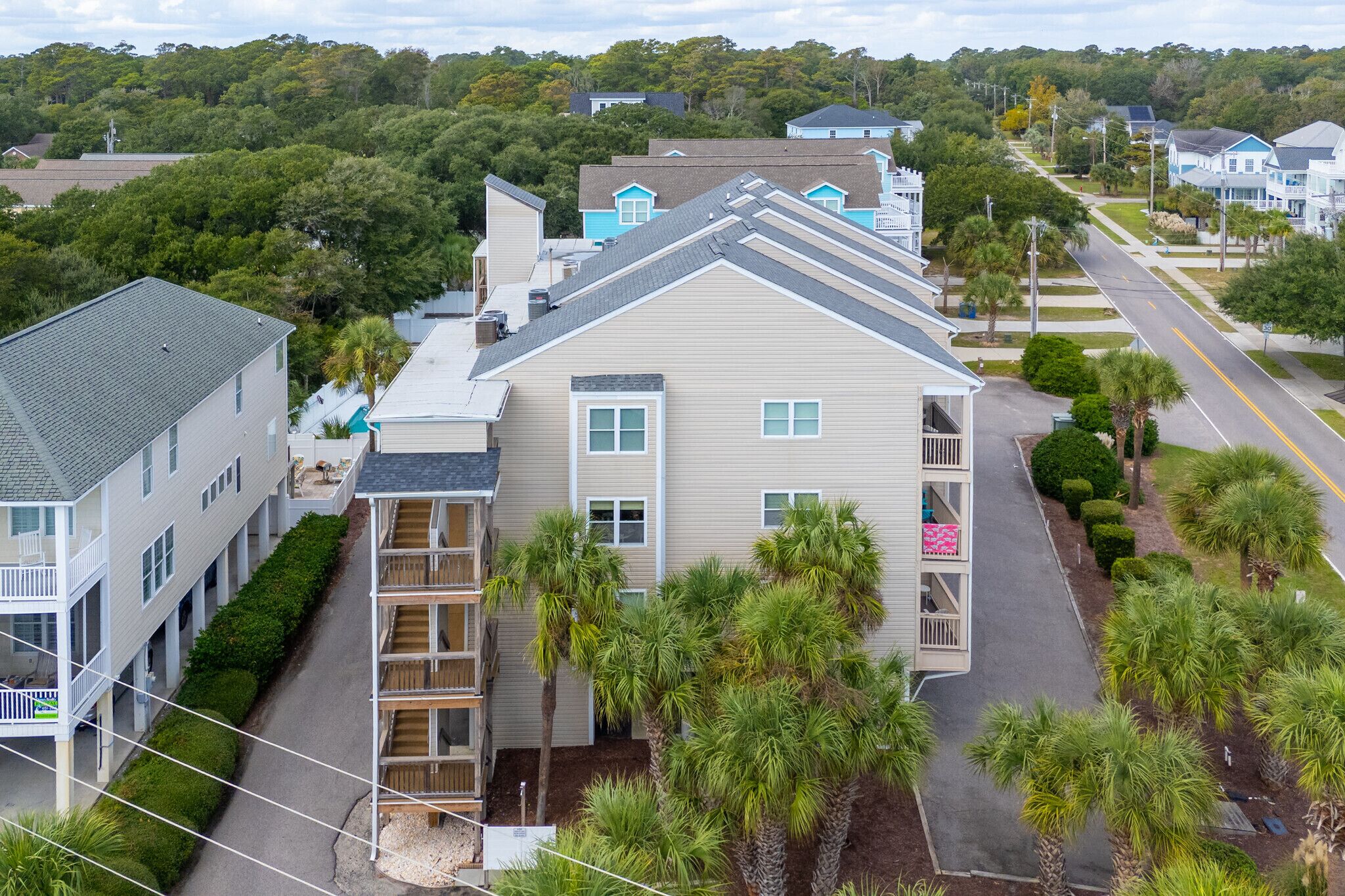 A multi-story residential building with a central courtyard, balconies, and a street view.