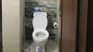 A bathroom with a toilet, a wall-mounted water heater, and a towel rack. - Tatvamasi Homestay (New Delhi)