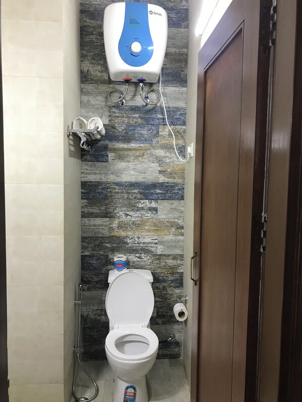 A bathroom with a toilet, a wall-mounted water heater, and a towel rack.