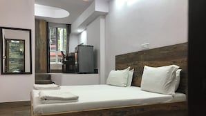 A modern bedroom with a wooden headboard, white bedding, and a neatly made bed. - Tatvamasi Homestay (New Delhi)
