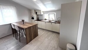 A modern kitchen with a wooden island, white cabinets, and a built-in oven. - Apartman Barbara (Sveti Filip i Jakov)