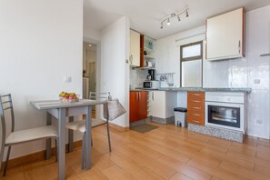 Une cuisine équipée d’une table à manger, de chaises, de placards, d’un four à micro-ondes, d’une cuisinière et d’une fenêtre.