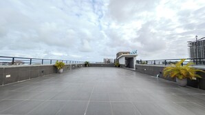 A rooftop terrace with a view of the sea, potted plants, and a building entrance. - Glassvine - 2D (Lagos)