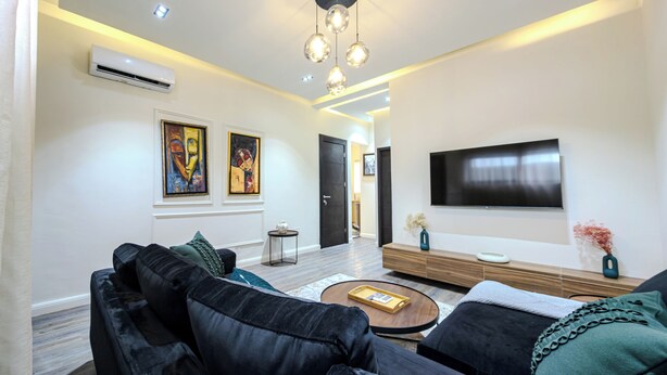 A modern living room with a sofa set, a coffee table, a flat-screen TV, and artwork on the walls. - Glassvine - 2D (Lagos)