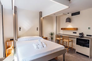 Une chambre d’hôtel moderne dotée d’un grand lit, d’une petite kitchenette, d’un coin repas et d’une salle de bain séparée.
