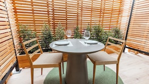 Une table ronde avec deux chaises, un tapis vert et un mur en bois à lattes en arrière-plan.