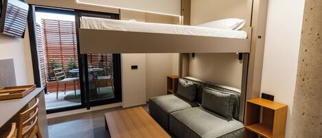 A modern room with a bunk bed, a sofa, a wooden table, and a TV.