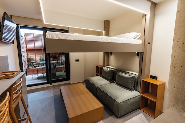A modern room with a bunk bed, a sofa, a wooden table, and a TV. - Motus Disruptive Apartments (València)