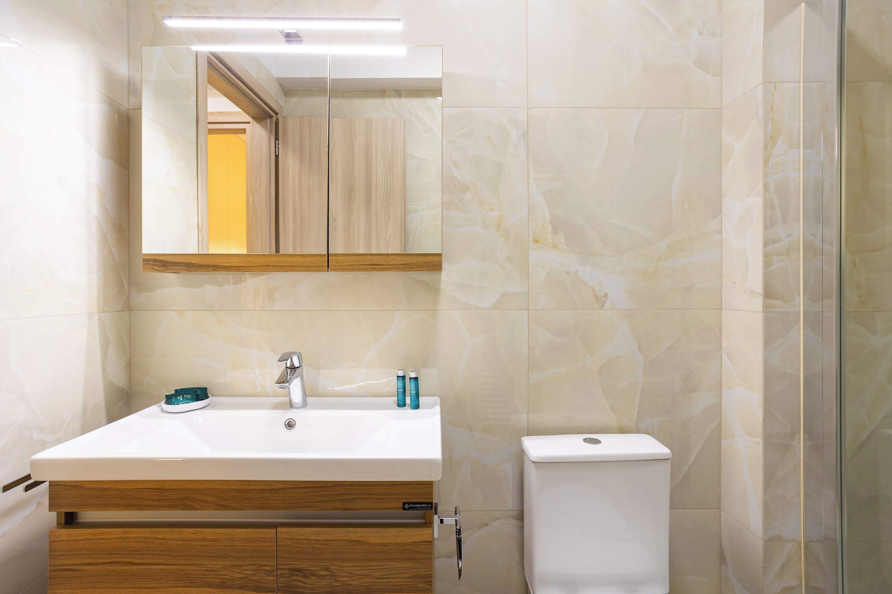 A bathroom with a white sink, mirror, and toilet.