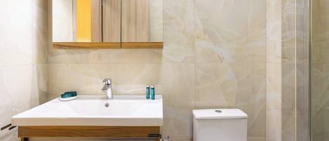 A bathroom with a white sink, mirror, and toilet.