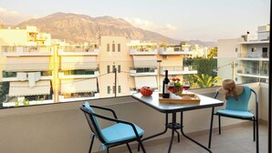Un balcone con un tavolo, due sedie, una bottiglia di vino, una zucca e un cappello.